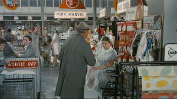 Movie still from “Playtime” (1967), directed by Jacques Tati – A man and a woman shopping in a store; Wide shot, Over the shoulder angle