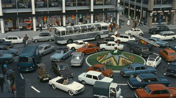 Movie still from “Playtime” (1967), directed by Jacques Tati – A busy street with many cars and buses on it; Extreme Wide shot, High angle
