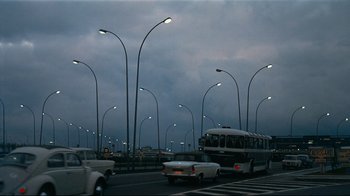 Movie still from “Playtime” (1967), directed by Jacques Tati – A bus driving down a street next to a street light; Extreme Wide shot, Low angle
