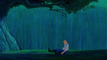 Movie still from “Pocahontas” (1995), directed by Mike Gabriel – A man sitting on the ground in front of a forest; Wide shot, High angle