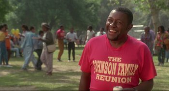 Movie still from “Poetic Justice” (1993), directed by John Singleton – A man in a pink shirt is smiling for the camera; Medium shot, Low angle