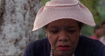 Movie still from “Poetic Justice” (1993), directed by John Singleton – An older woman wearing a pink hat sitting in front of a tree; Close Up shot, Low angle