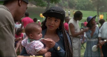 Movie still from “Poetic Justice” (1993), directed by John Singleton – A woman holding a baby in her arms while standing in a park; Close Up shot, Over the shoulder angle