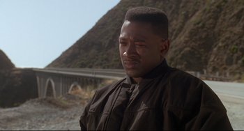 Movie still from “Poetic Justice” (1993), directed by John Singleton – A man in a black shirt is looking down; Close Up shot, Over the shoulder angle