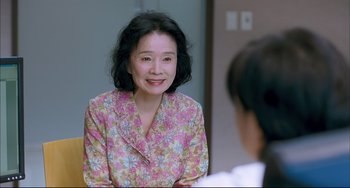 A woman wearing a floral shirt is looking at the camera