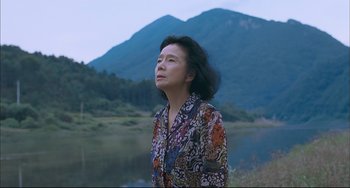 An older woman standing in front of a body of water