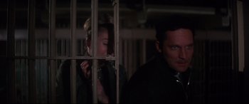 Movie still from “Point Blank” (1967), directed by John Boorman – A woman standing next to a man behind bars; Close Up shot, Low angle