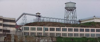 Movie still from “Point Blank” (1967), directed by John Boorman – A building on a hill with a water tower on top of it; Extreme Wide shot, Low angle