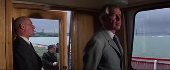 Movie still from “Point Blank” (1967), directed by John Boorman – A man in a suit and tie standing in front of a door; Medium shot, Low angle