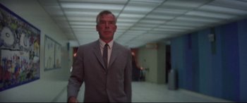 Movie still from “Point Blank” (1967), directed by John Boorman – A man in a suit and tie standing in a room; Medium shot, Low angle
