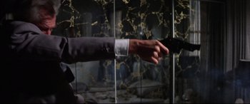 Movie still from “Point Blank” (1967), directed by John Boorman – A man in a gray suit is reaching out to grab something in his hand; Medium shot, Low angle