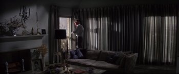 Movie still from “Point Blank” (1967), directed by John Boorman – A man standing in a living room looking out a window; Wide shot, Low angle