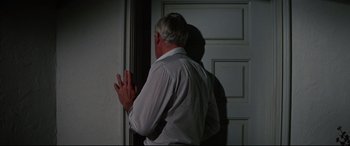 Movie still from “Point Blank” (1967), directed by John Boorman – An older man standing in front of a white door; Medium shot, Over the shoulder angle