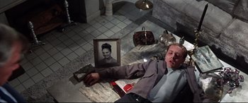 Movie still from “Point Blank” (1967), directed by John Boorman – A man laying on the floor next to an old picture; Medium shot, Overhead angle