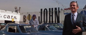 Movie still from “Point Blank” (1967), directed by John Boorman – A man standing in front of some cars in a parking lot; Wide shot, Low angle