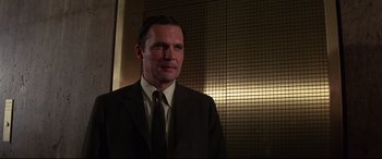 Movie still from “Point Blank” (1967), directed by John Boorman – A man wearing a suit and tie standing in front of a wall; Close Up shot, Low angle