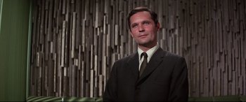 Movie still from “Point Blank” (1967), directed by John Boorman – A man wearing a suit and tie standing in front of a wall; Close Up shot, Low angle
