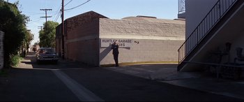Movie still from “Point Blank” (1967), directed by John Boorman – A man standing in front of a garage door; Wide shot, High angle