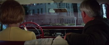 Movie still from “Point Blank” (1967), directed by John Boorman – The interior of an old car with a view of a building through a window; Wide shot, Over the shoulder angle