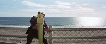 Movie still from “Point Blank” (1967), directed by John Boorman – A man standing next to a fence looking at the ocean; Wide shot, Low angle