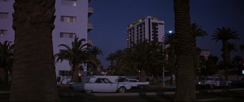 Movie still from “Point Blank” (1967), directed by John Boorman – A car parked on the side of the road near palm trees at night; Extreme Wide shot, Low angle