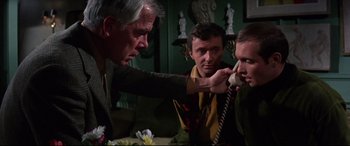 Movie still from “Point Blank” (1967), directed by John Boorman – A group of men standing around a table; Medium shot, Low angle