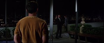 Movie still from “Point Blank” (1967), directed by John Boorman – A man in a suit and tie standing in front of a window; Wide shot, Over the shoulder angle