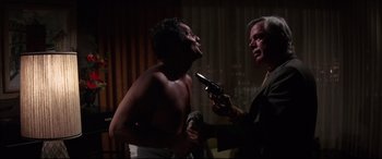 Movie still from “Point Blank” (1967), directed by John Boorman – A man holding a gun while another man holds a microphone; Medium shot, Over the shoulder angle