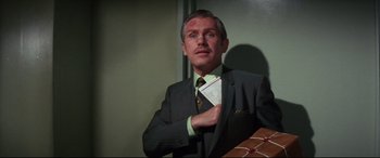 Movie still from “Point Blank” (1967), directed by John Boorman – A man in a suit holding a piece of paper; Medium shot, Low angle