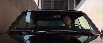 Movie still from “Point Blank” (1967), directed by John Boorman – A man sitting in the driver's seat of a black car; Medium shot, Low angle
