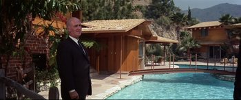 Movie still from “Point Blank” (1967), directed by John Boorman – An older man standing in front of a swimming pool; Wide shot, Low angle