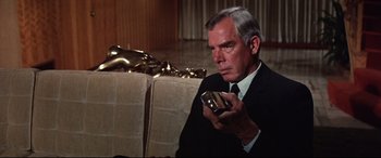 Movie still from “Point Blank” (1967), directed by John Boorman – An older man in a suit and tie holding a cell phone; Medium shot, High angle