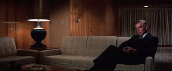 Movie still from “Point Blank” (1967), directed by John Boorman – A couch in a living room next to a wooden wall; Wide shot, High angle