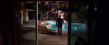 Movie still from “Point Blank” (1967), directed by John Boorman – A man standing in front of a pool at night; Extreme Wide shot, High angle