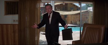Movie still from “Point Blank” (1967), directed by John Boorman – A man in a suit and tie holding a briefcase in front of a pool; Medium shot, Low angle
