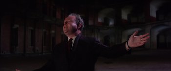 Movie still from “Point Blank” (1967), directed by John Boorman – A man in a suit and tie in a dark room; Medium shot, Low angle