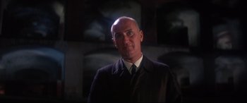 Movie still from “Point Blank” (1967), directed by John Boorman – A man in a suit and tie standing in front of a wall; Close Up shot, Low angle