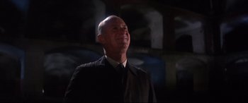 Movie still from “Point Blank” (1967), directed by John Boorman – A bald man in a black jacket and a black tie; Close Up shot, Low angle