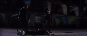Movie still from “Point Blank” (1967), directed by John Boorman – Three men standing around a dead body on the ground; Wide shot, Low angle