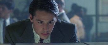 Movie still from “Point Break” (1991), directed by Kathryn Bigelow – A man in a business suit looking down at a computer screen; Close Up shot, Over the shoulder angle