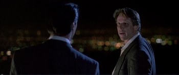 Movie still from “Point Break” (1991), directed by Kathryn Bigelow – Two men in suits are standing in front of a city skyline at night; Close Up shot, Over the shoulder angle