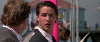 Movie still from “Point Break” (1991), directed by Kathryn Bigelow – A person wearing a suit and tie; Close Up shot, Over the shoulder angle