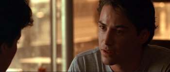 Movie still from “Point Break” (1991), directed by Kathryn Bigelow – A person sitting down looking at the camera; Close Up shot, Over the shoulder angle