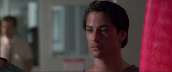 Movie still from “Point Break” (1991), directed by Kathryn Bigelow – A person wearing a blue shirt; Close Up shot, Over the shoulder angle