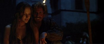 Movie still from “Point Break” (1991), directed by Kathryn Bigelow – A man and a woman are posing for a picture; Medium shot, Over the shoulder angle