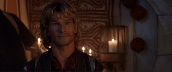 Movie still from “Point Break” (1991), directed by Kathryn Bigelow – A person with a candle in the background; Close Up shot, Over the shoulder angle