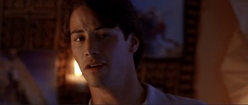 Movie still from “Point Break” (1991), directed by Kathryn Bigelow – A man's face in a dark room; Close Up shot, Over the shoulder angle