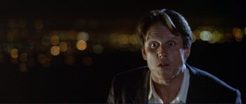 Movie still from “Point Break” (1991), directed by Kathryn Bigelow – A person wearing a suit and smoking a cigarette; Close Up shot, Low angle