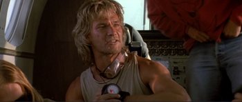 Movie still from “Point Break” (1991), directed by Kathryn Bigelow – A man with long blonde hair holding a stopwatch; Close Up shot, Low angle