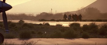 Movie still from “Point Break” (1991), directed by Kathryn Bigelow – A group of people walking down a dirt road; Extreme Wide shot, Low angle